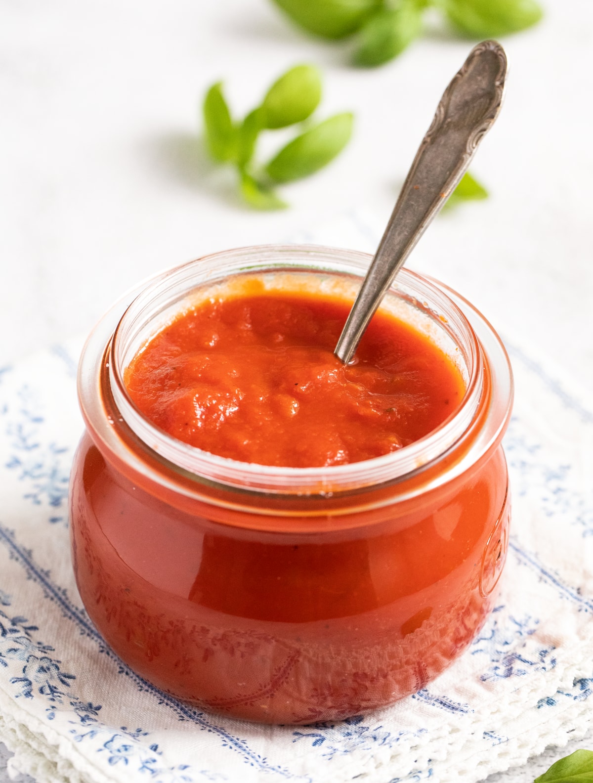 small jar with italian tomato sugo with a spoon in it.