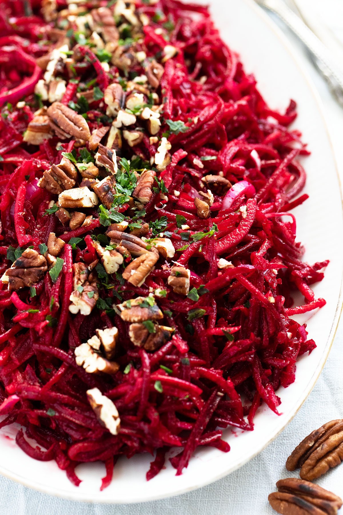 close up platter with grated raw beet salad with apples and pecans.