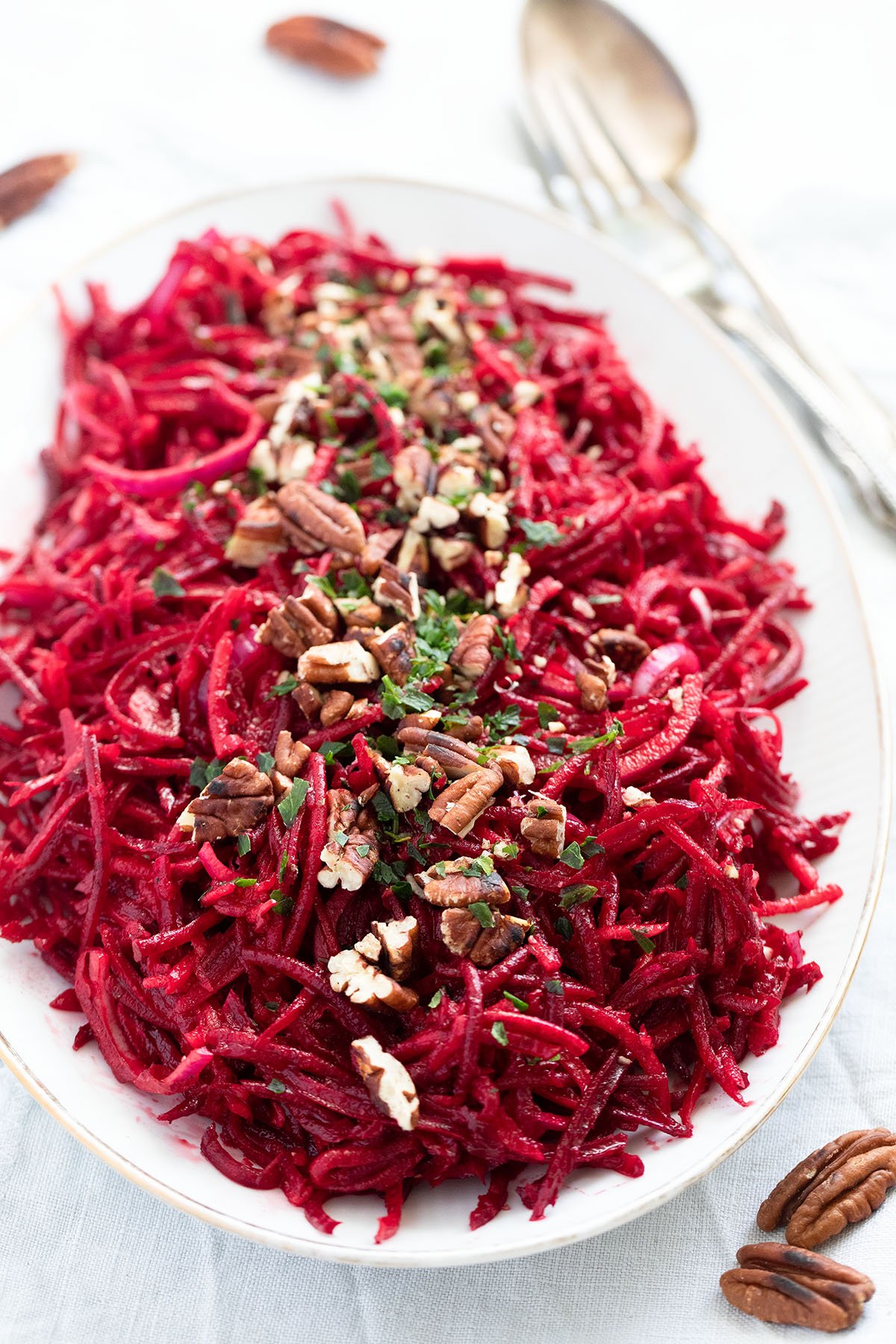 long platter loaded with raw beet salad with apples and pecans.