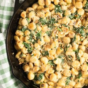 close up spinach gnocchi sprinkled with fresh herbs.