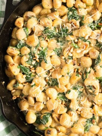 close up spinach gnocchi sprinkled with fresh herbs.