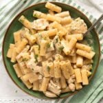 close up chicken parmesan garlic pasta in a green bowl.