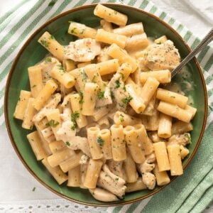 close up chicken parmesan garlic pasta in a green bowl.