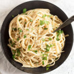 black bowl full of cream cheese pasta sprinkled with parsley.