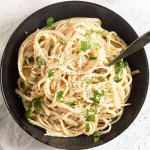 black bowl full of cream cheese pasta sprinkled with parsley.
