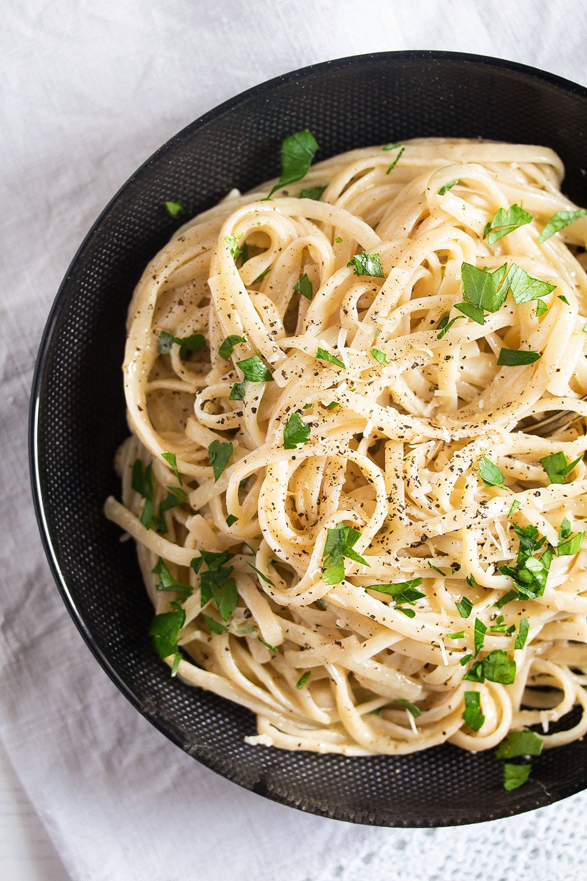 close up pasta with cream cheese sauce and parsley in a bowl.