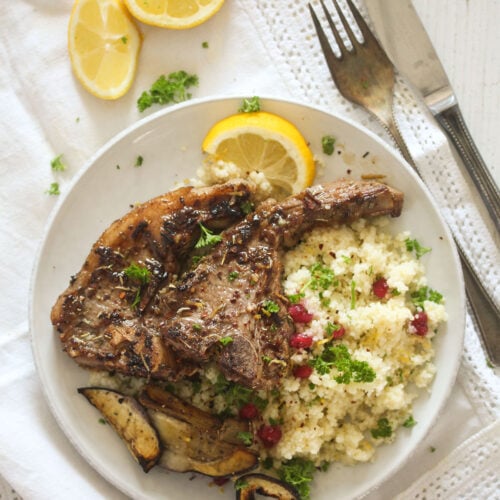 plate with turkish marinated lamb chops served with bulgur and lemon wedges.