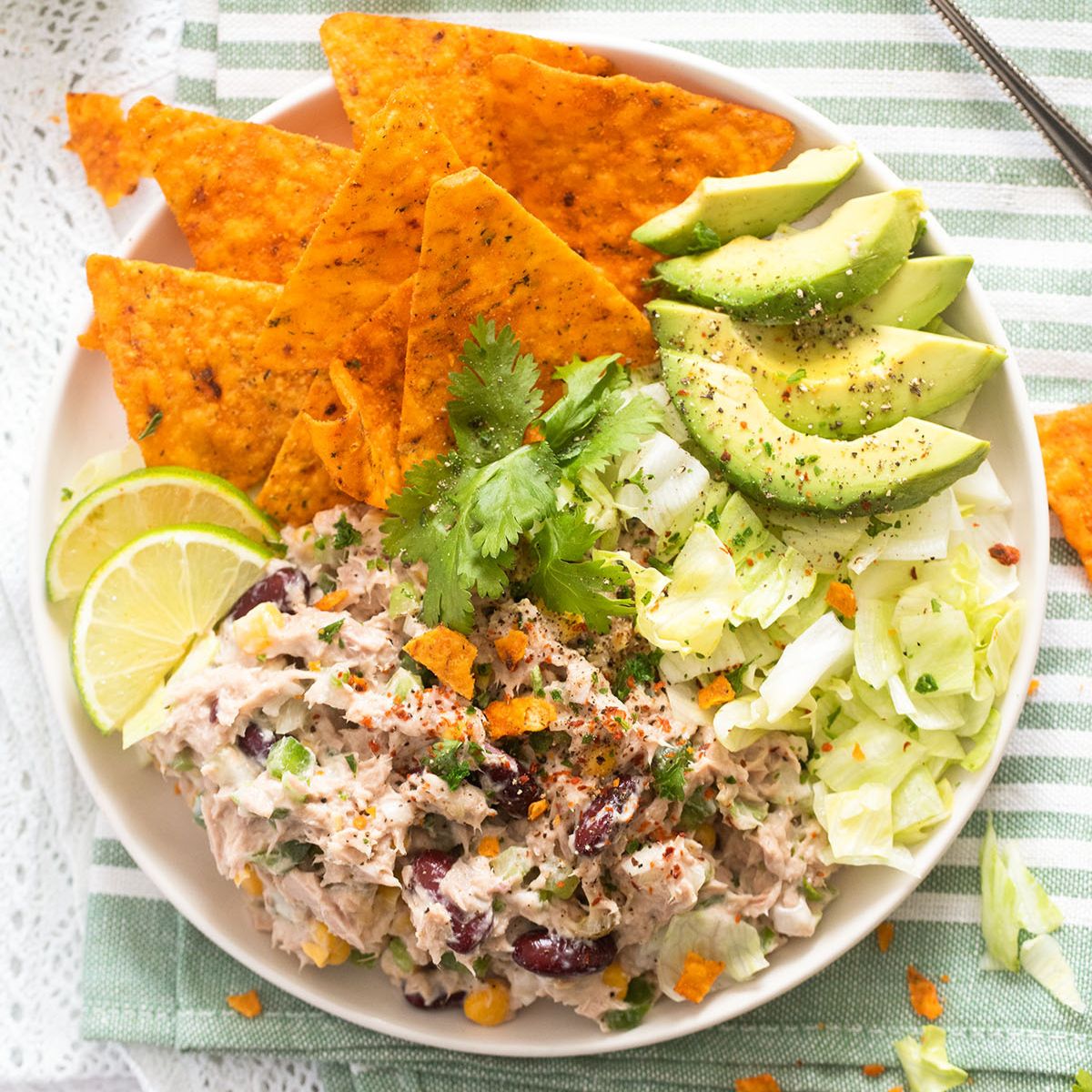 mexican tuna salad with tortilla chips, avocado and lime wedges.