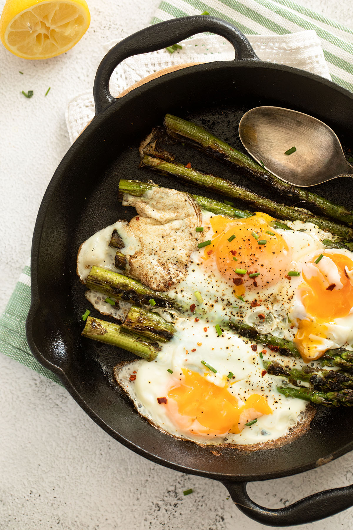 fried asparagus spears topped with fried eggs in a skillet.