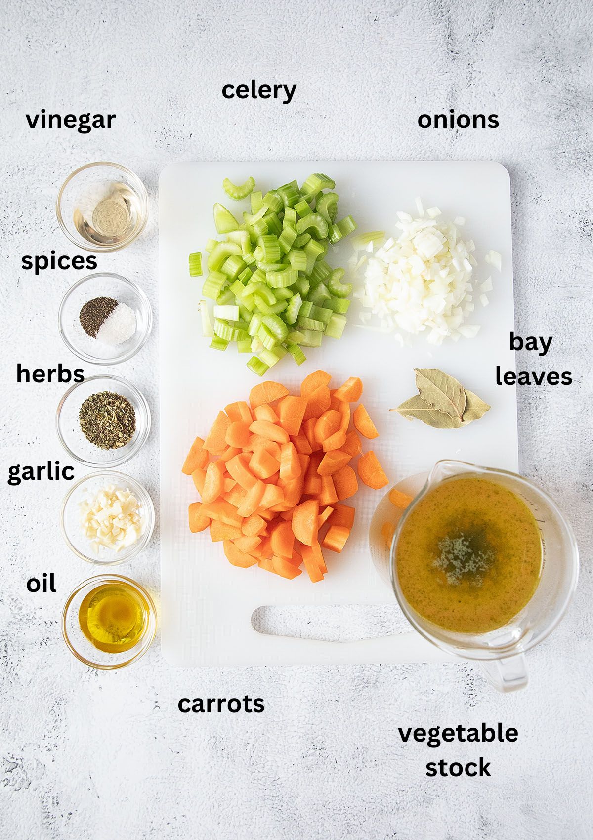 listed ingredients for making soup with carrots, celery, onion and spices on the table.