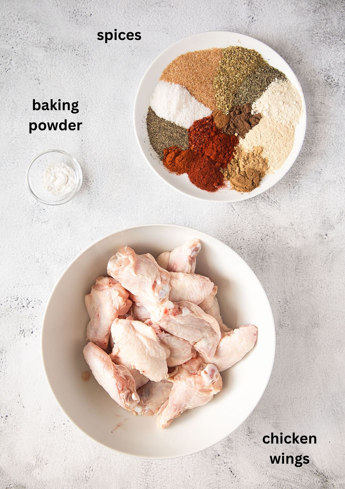bowls with raw chicken wings, baking powder and spices.