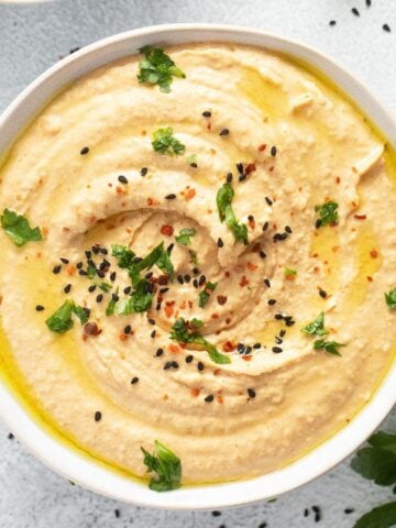 overhead view of creamy butter bean hummus in a white bowl.
