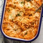 golden leftover spaghetti bake topped with cheese, a fork with tangled noodles on it.