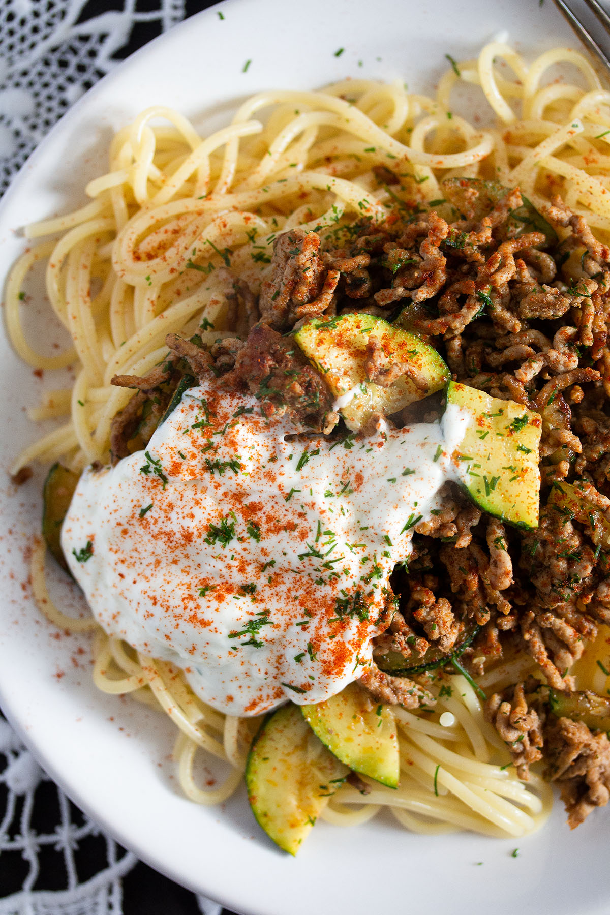 close up of a plate with spaghetti, minced meat and yogurt.