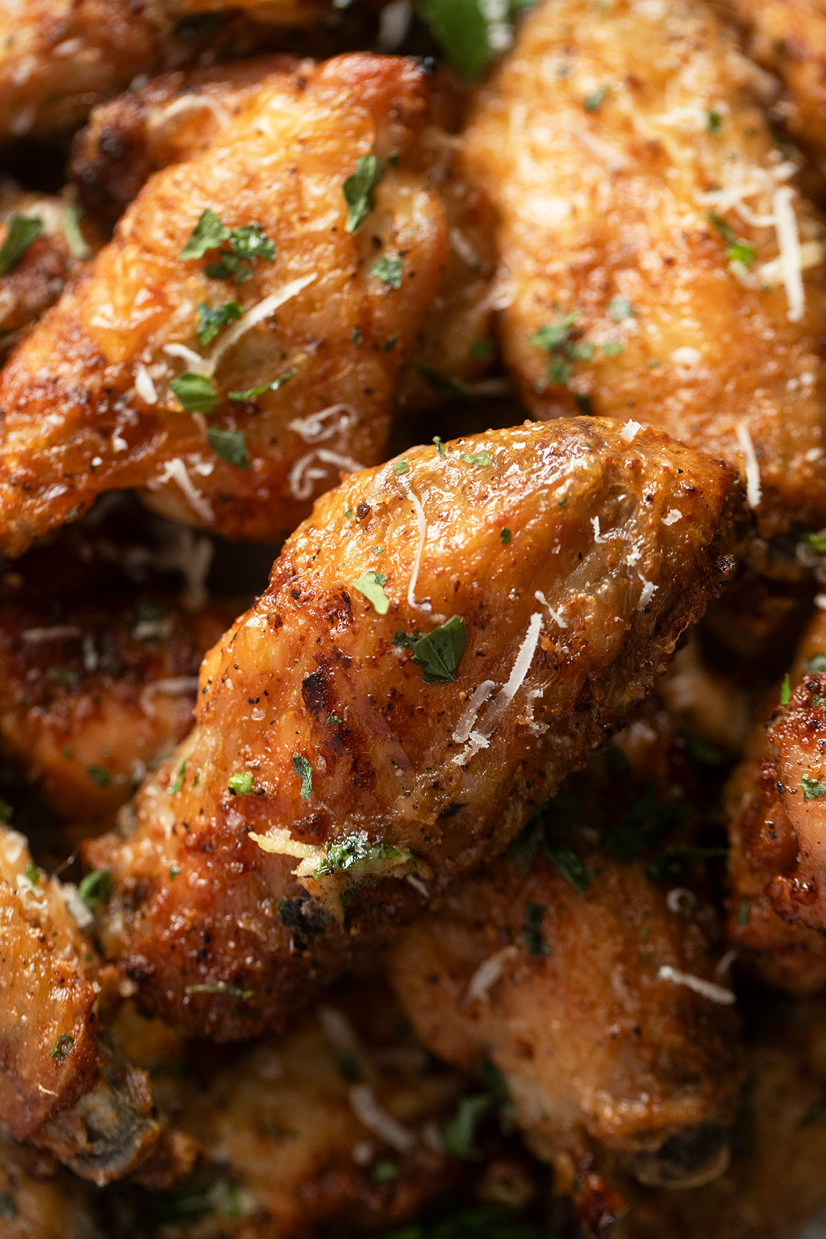 close up chicken wings tossed with parmesan garlic sauce.