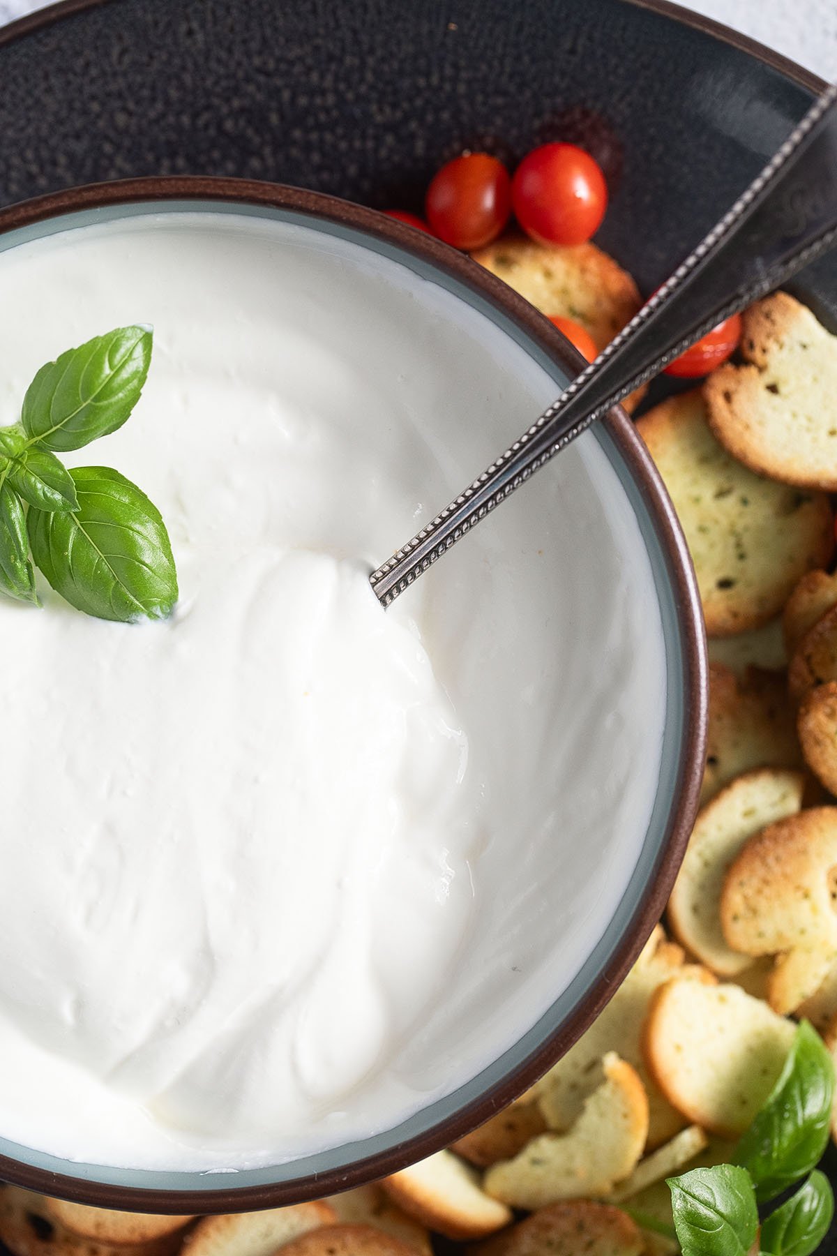 a bowl of whipped cottage cheese with basil leaves on top.