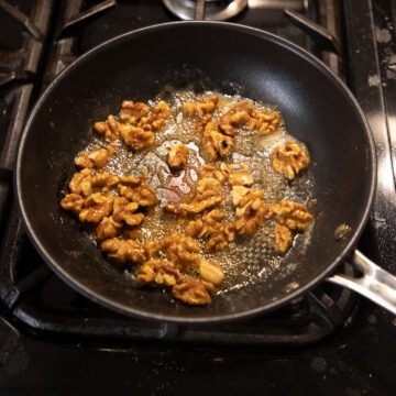 caramelizing walnut halves with honey in a pan.