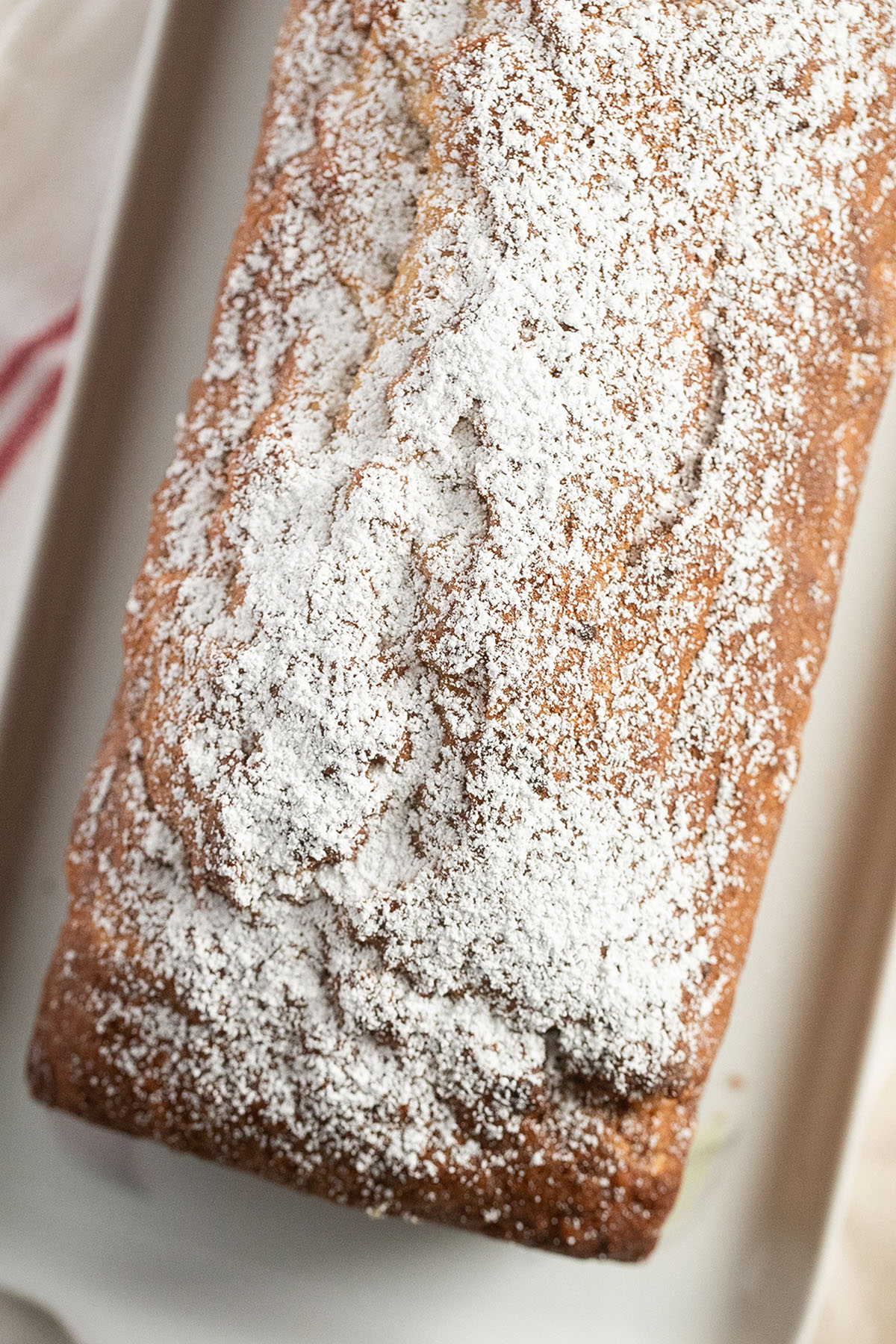loaf of banana bread with pecans sprinkled with powdered sugar.