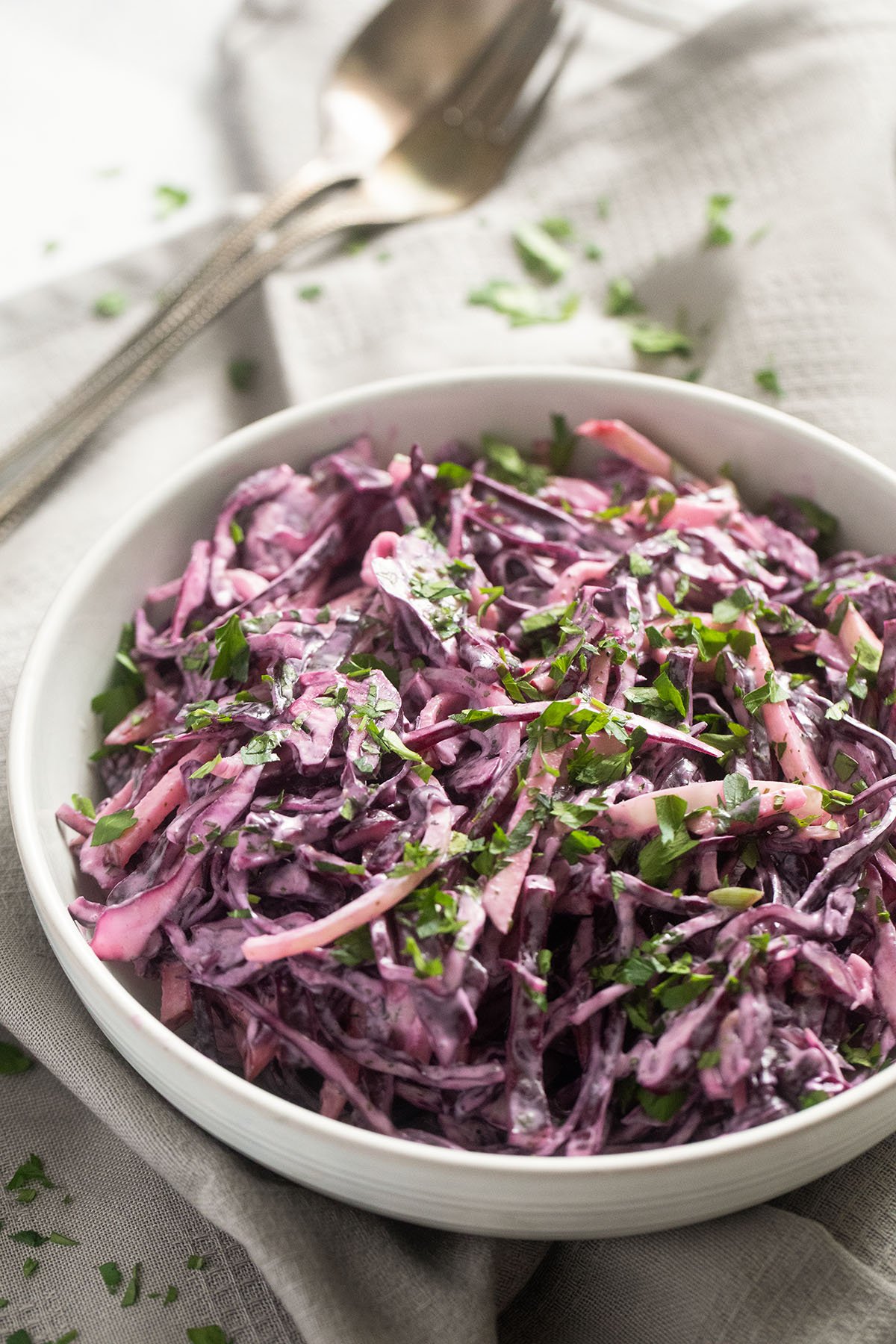 a bowl with red cabbage coleslaw with creamy dressing and a spoon.