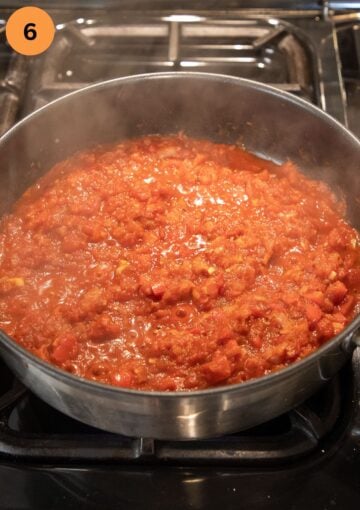 adding canned tomatoes to a skillet on the stove top.