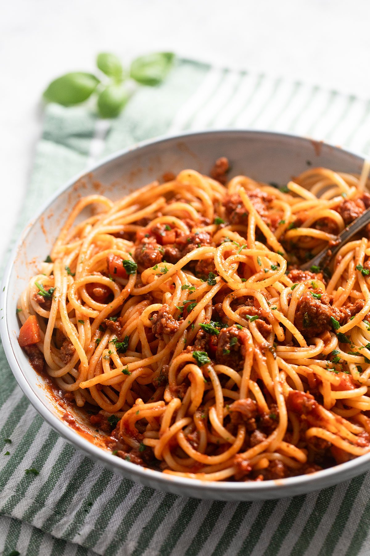 bowl with spaghetti with turkey and tomato sauce on a striped kitched cloth.