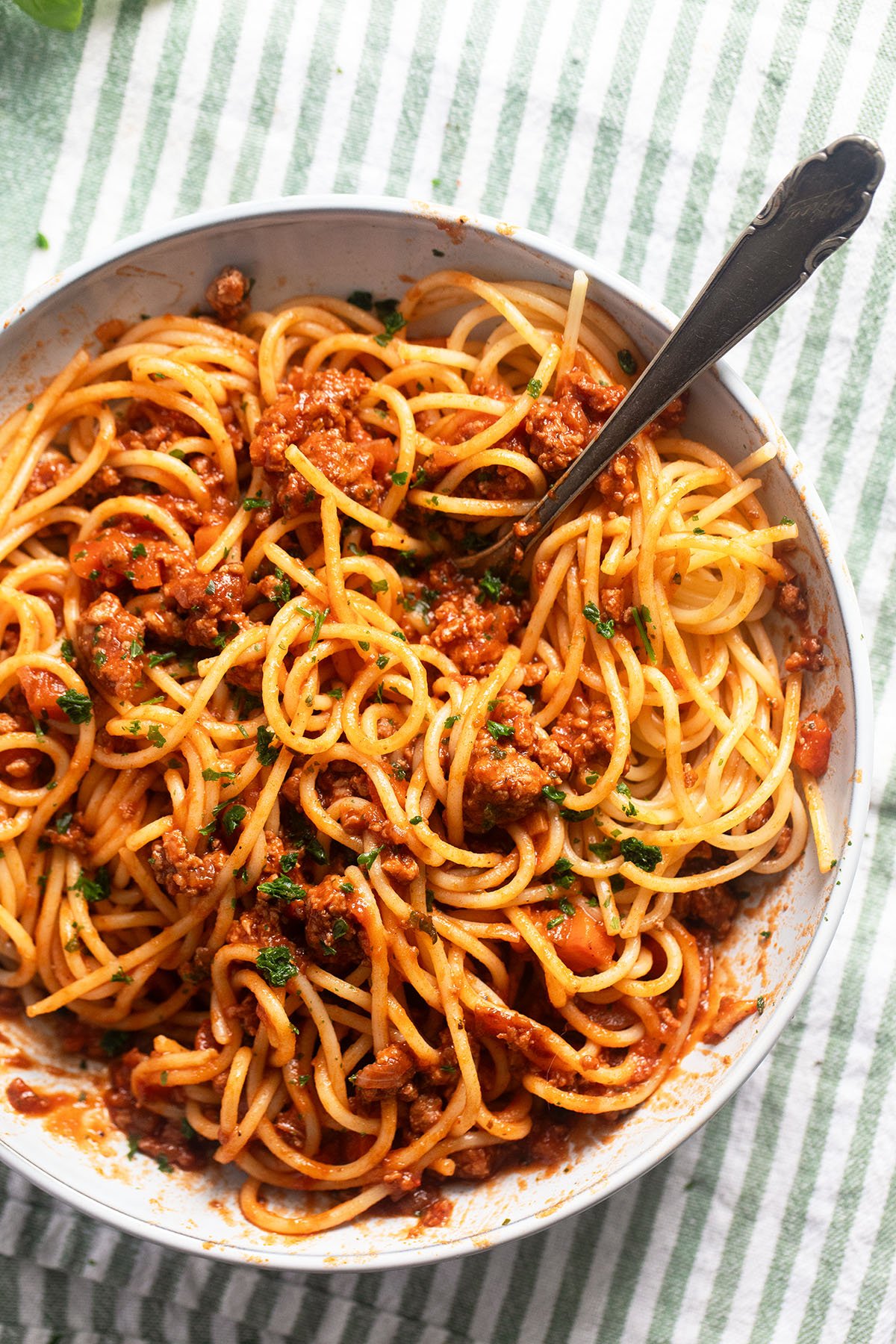 tangled spaghetti with turkey bolognese in a bowl with a fork.