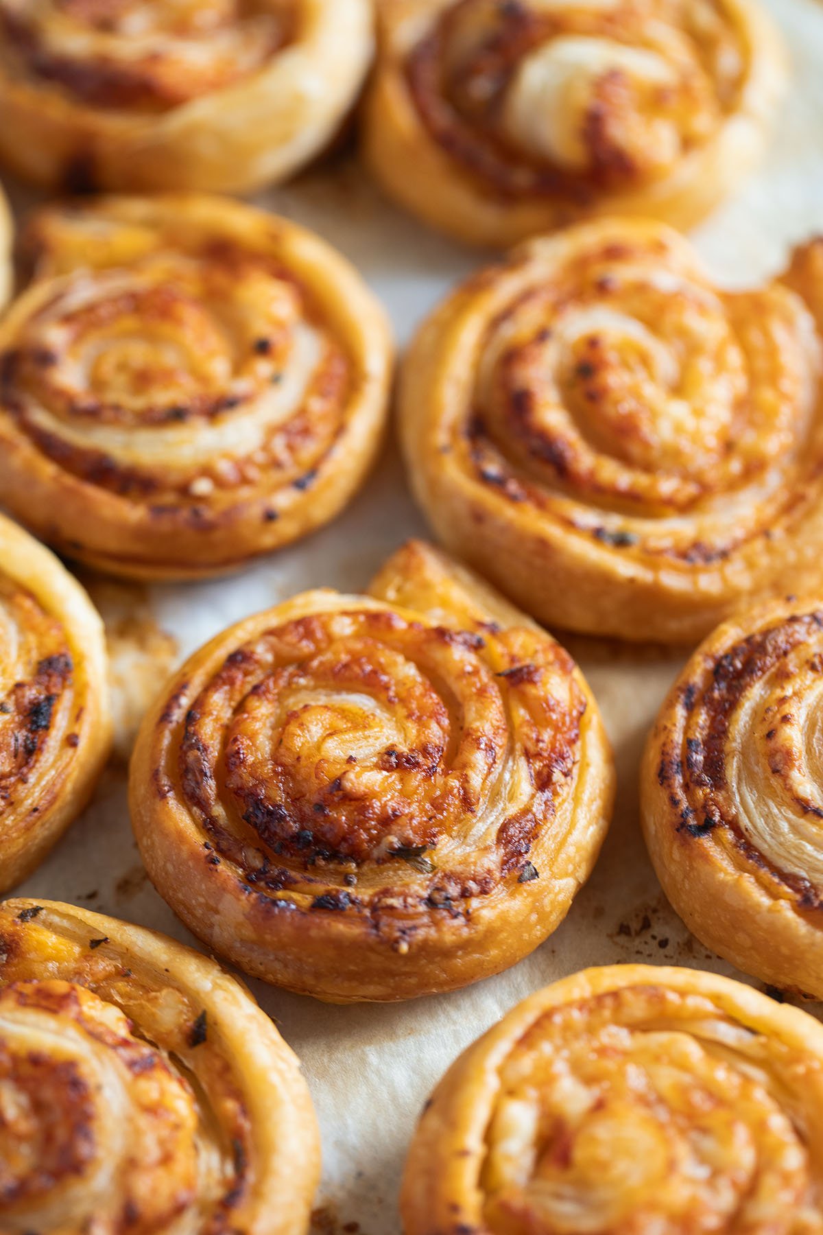 cheesy puff pastry pinwheels on a baking tray.