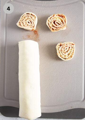 filled and rolled puff pastry and a few cut pinwheels on a cutting board.