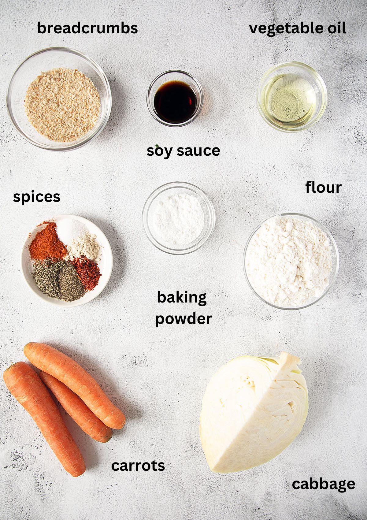labeled ingredients for making fritters with cabbage, carrots, breadcrumb, flour and spices on the table.