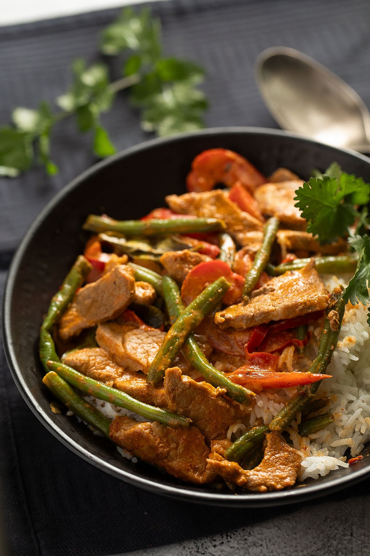 red thai curry with pork, coconut milk and vegetables in a large bowl.