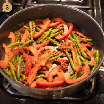 stir-frying green beans and sliced peppers in a pan.