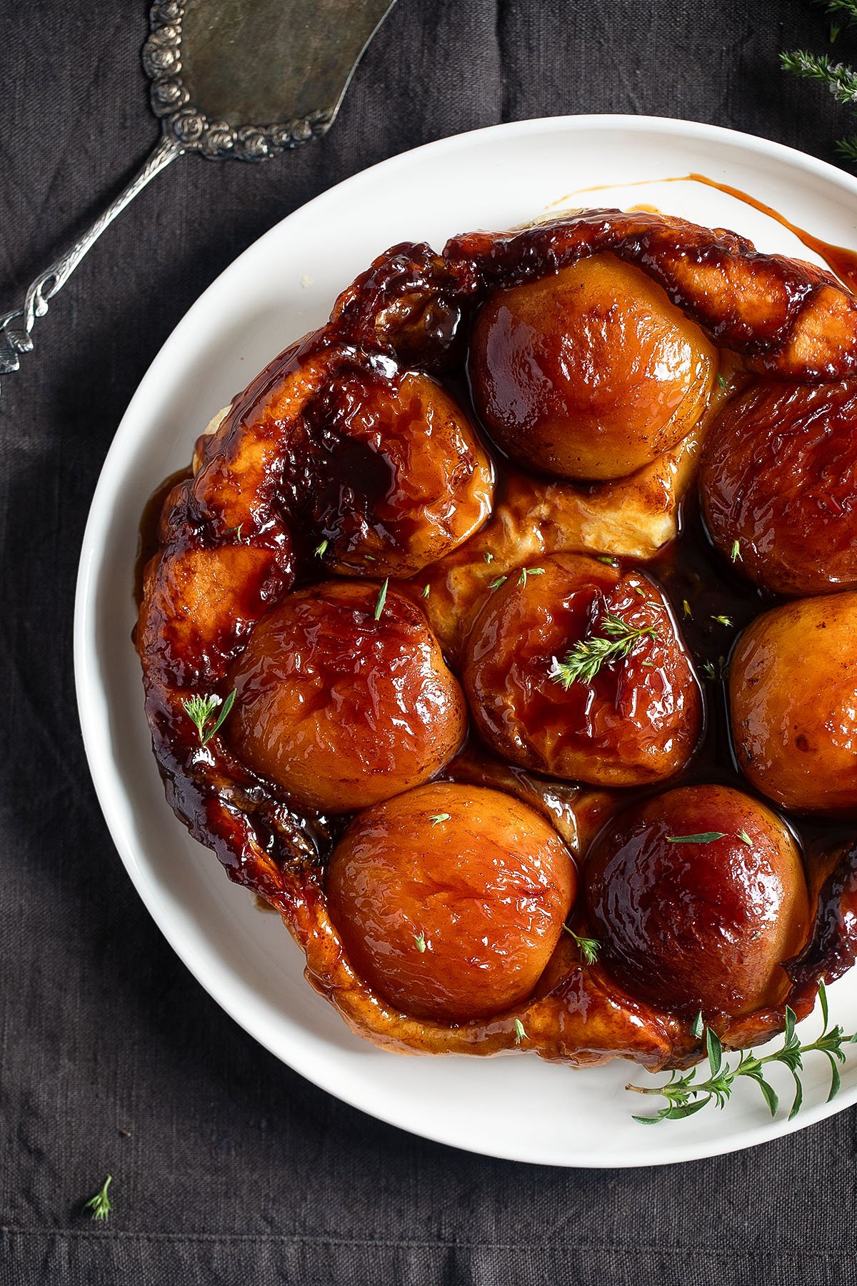 tarte tatin made with peach halves and puff pastry and decorated with fresh thyme.