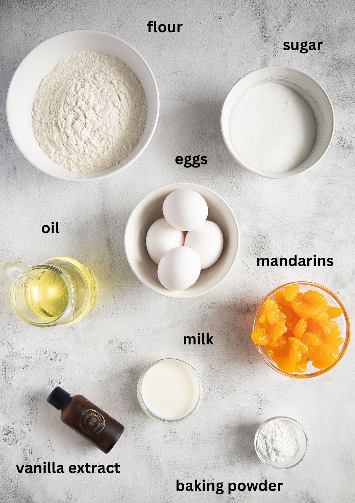 labeled ingredients for making muffins with mandarin oranges, eggs, oil, flour.