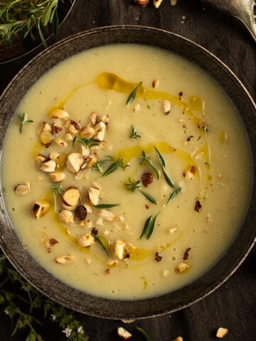 bowl with celeriac apple soup topped with roasted hazelnuts and thyme.