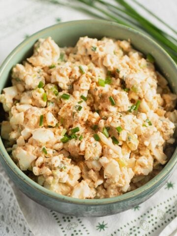 bowl full of egg salad with cottage cheese and fresh chives beside it.