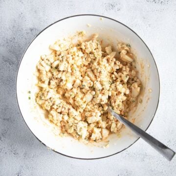 cottage cheese egg mixture stirred with a spoon in a bowl.