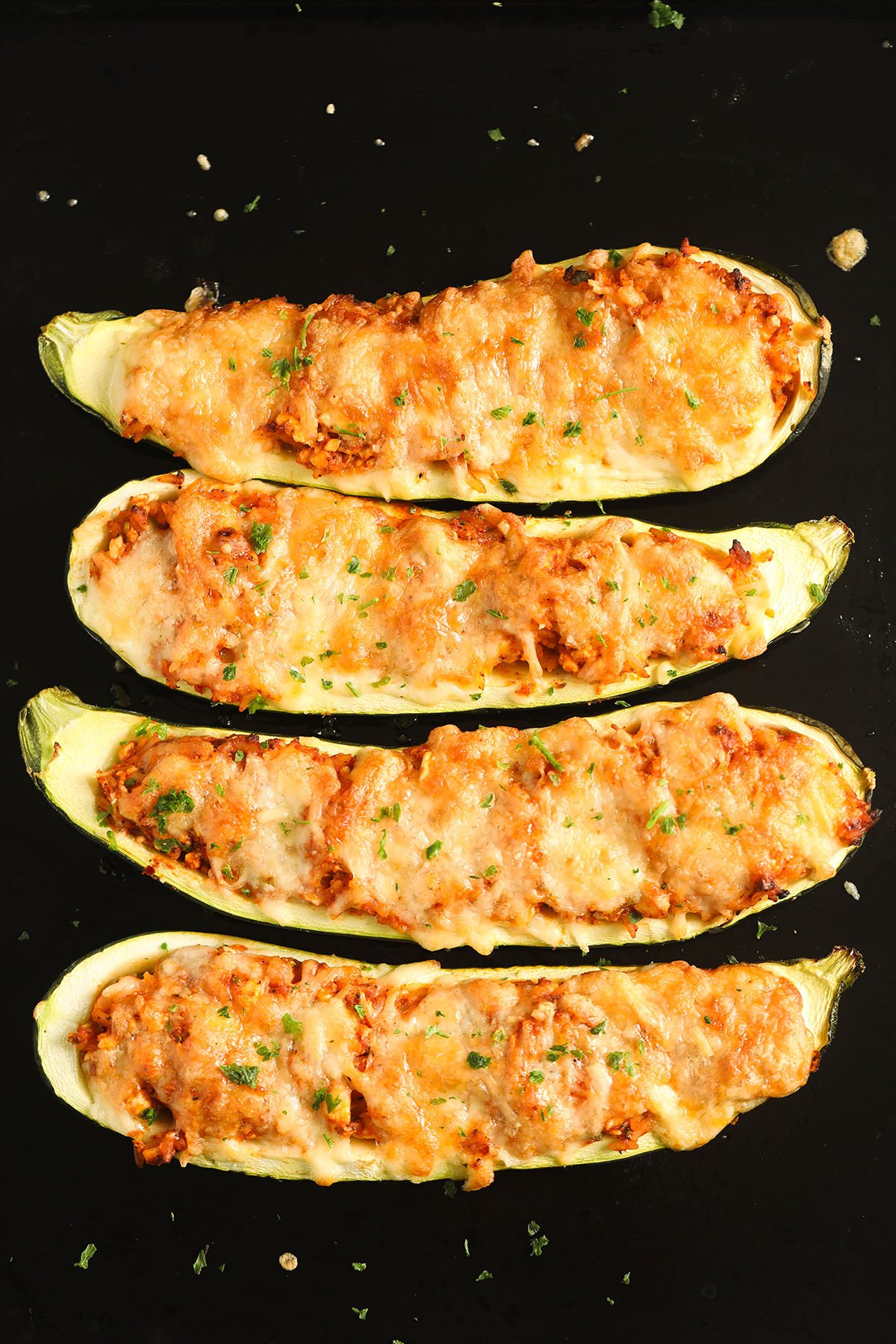 four zucchini boats stuffed with rice and topped with melted cheese.