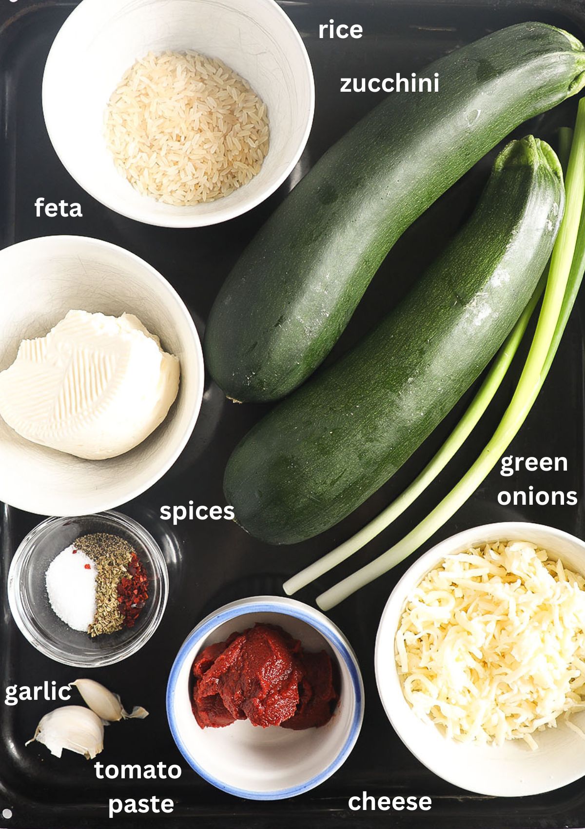 labeled ingredients for making stuffed zucchini with rice, grated mozzarella, feta, green onions and tomato paste.