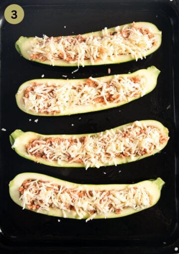 four zucchini boats on a baking sheet before baking.