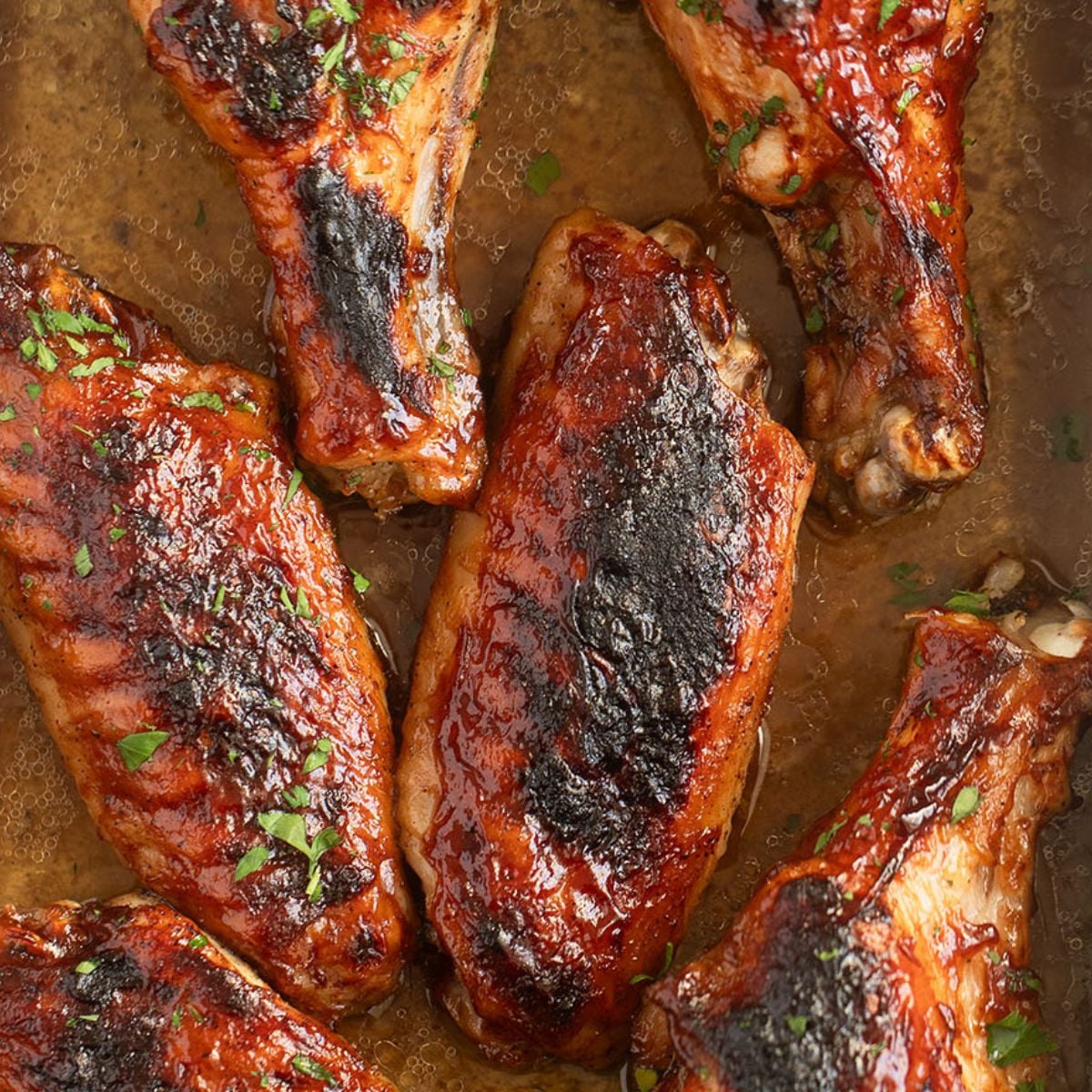many crispy baked turkey wings sprinkled with fresh parsley.