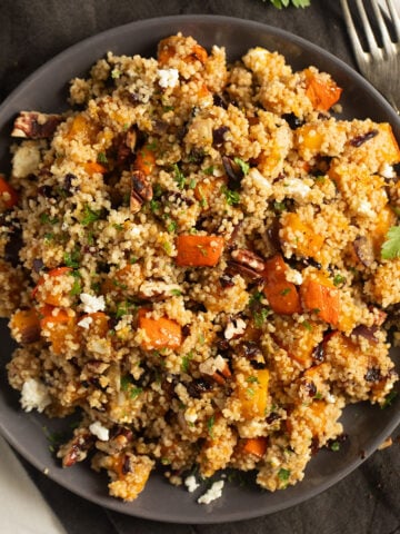 couscous and pumpkin salad in a large brown bowl with a fork beside it.