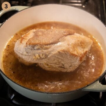 a piece of turkey breast with skin simmering with onions in chicken stock.