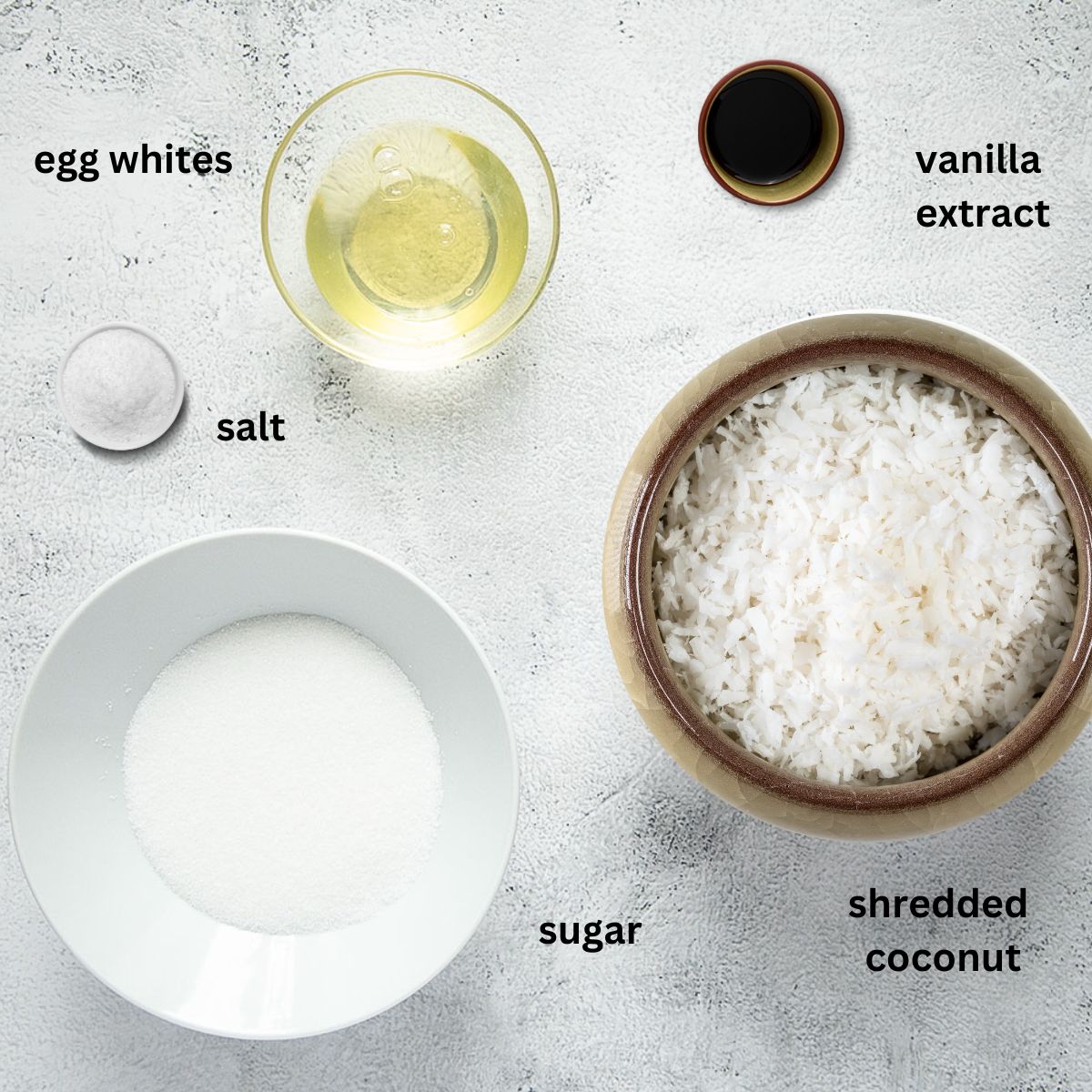 bowls with shredded coconut, sugar, vanilla extract, egg whites and salt for making macaroons.