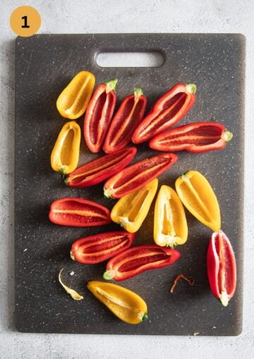 many red and yellow raw mini pepper halves on a cutting board.