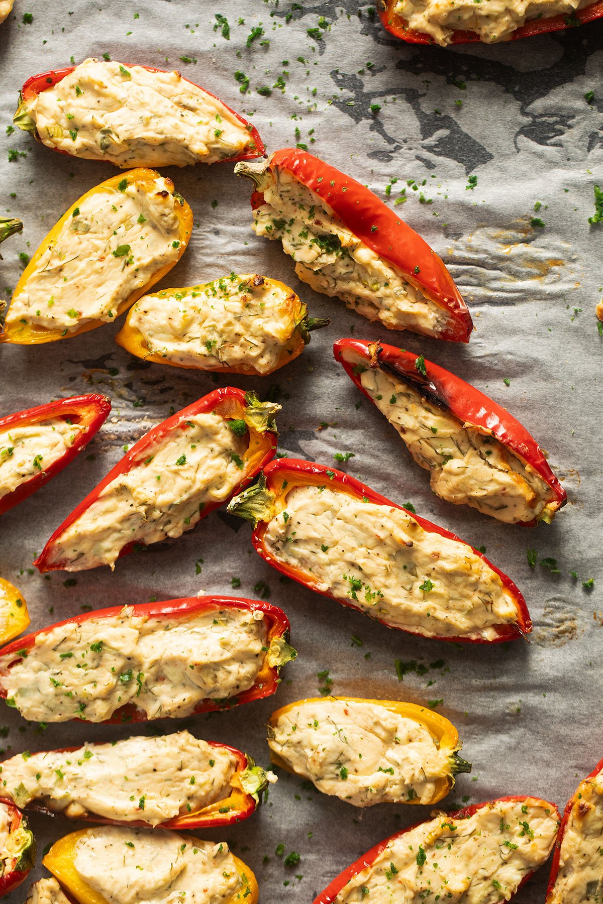 many red and yellow pepper halves stuffed with cheese on a baking sheet.