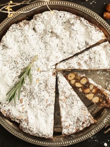 italian fruitcake thickly sprinkled with powdered sugar with three cut slices.