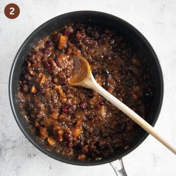 mixing dried fruit, canned pineapple, and butter for making fruitcake in a saucepan.