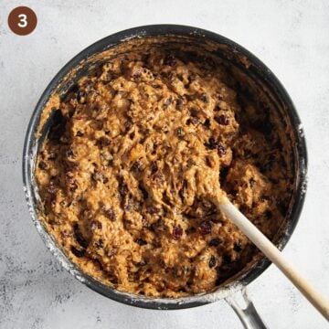 mixture of boiled crushed pineapple, dried fruit, flour, and butter in a saucepan with a wooden spoon in it.