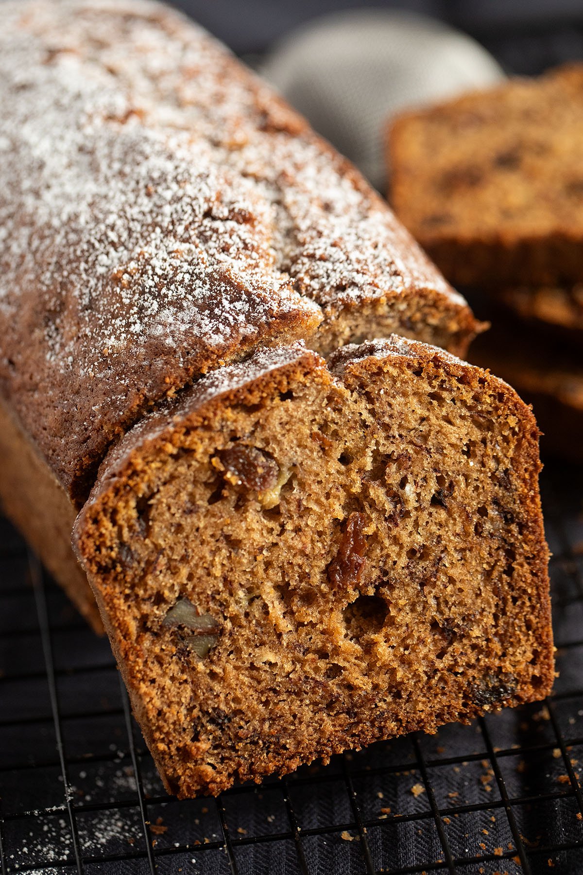 a loaf of raisin banana bread, one slice showing the crumb.