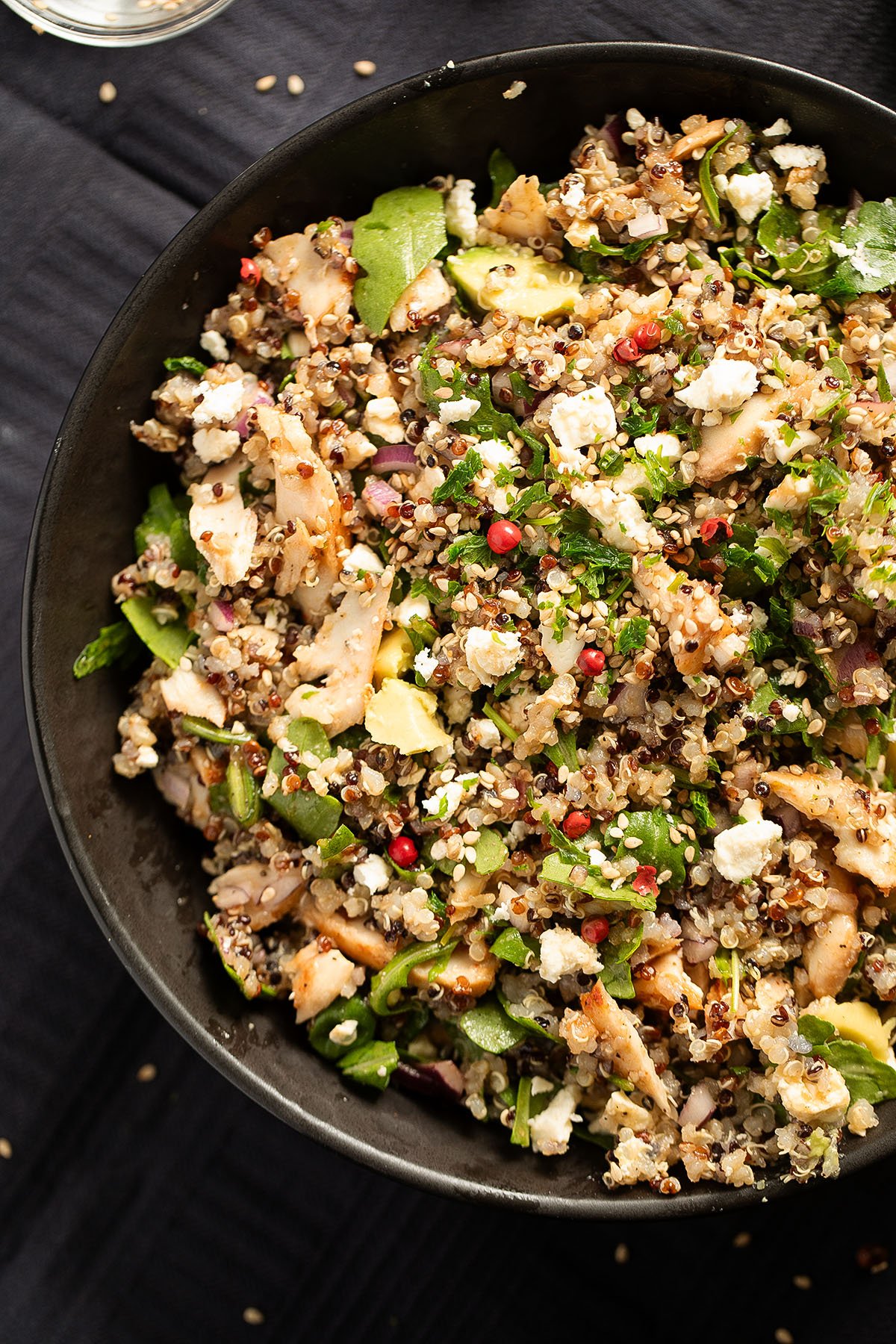 salmon and quinoa salad with arugula and feta in a dark bowl.